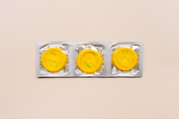 Colorful composition with yellow condoms on beige surface. safe sex and contraceptive concept