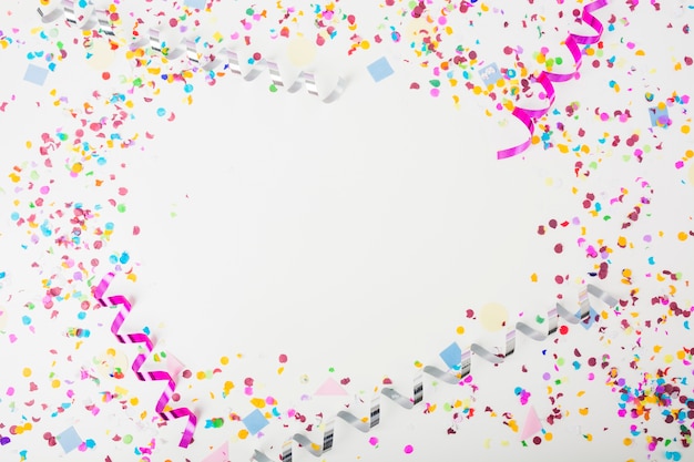 Colorful confetti and curling streamers on white background with space for text