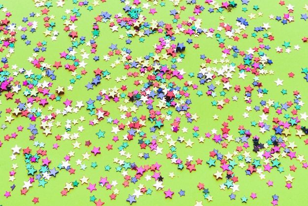 Colorful confetti stars on green background