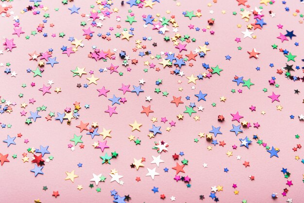 Colorful confetti stars on pink background