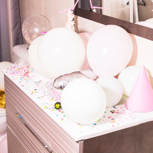 Colorful confetti and white balloons on wooden desk