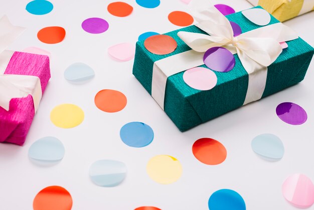 Colorful confetti on wrapped gift box with ribbon against white background