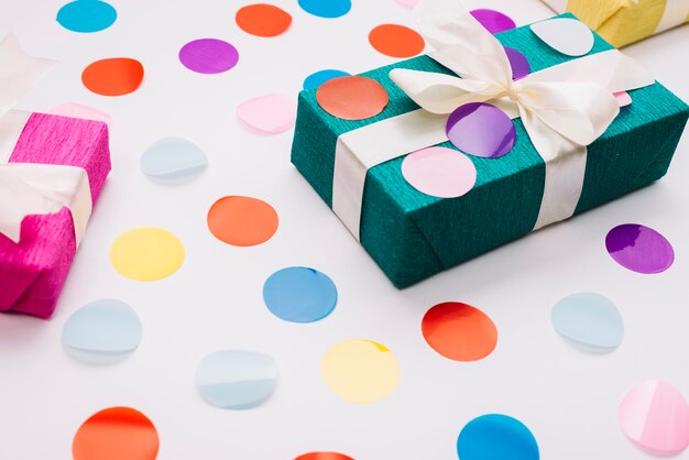 Красочный конфетти на подарочной коробке с лентой на белом фоне