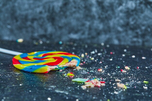 Colorful cracked lollipop on blue background.