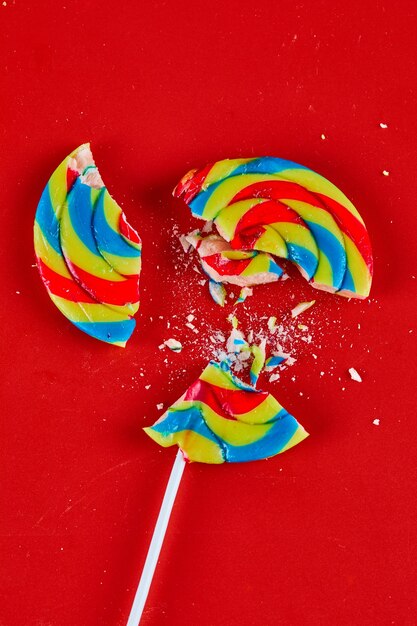 Colorful cracked lollipop on red surface.