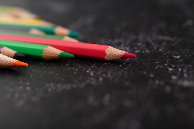 Colorful crayon pencils with triangle shape on black surface with copy space.