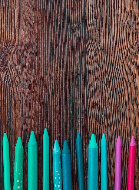 Free photo colorful crayons arranged at the bottom of wooden background