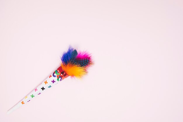 Colorful decorative feather cone against pink background