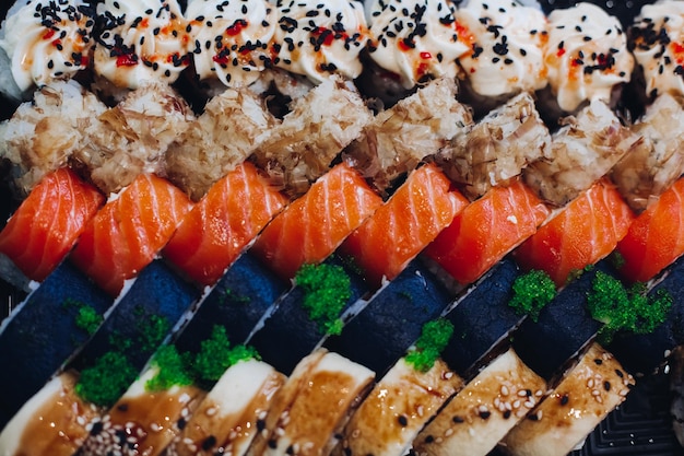 Colorful delicious mouthwatering sushi set laying on the plate including different ingredients fish caviar rice cucumber salmon soy sauce wasabi sesame seeds An interesting presentation