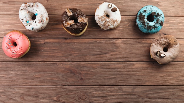 Free photo colorful donuts on wooden background