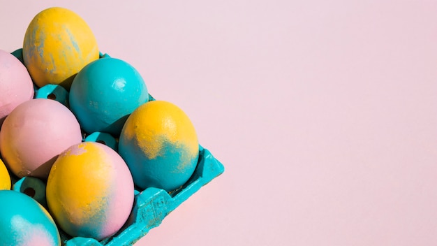 Colorful Easter eggs in blue rack on pink table