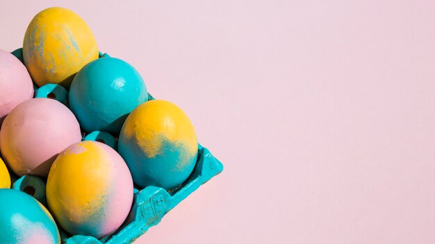 Красочные пасхальные яйца в синей стойке на розовом столе