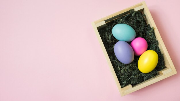 Colorful Easter eggs in box on table