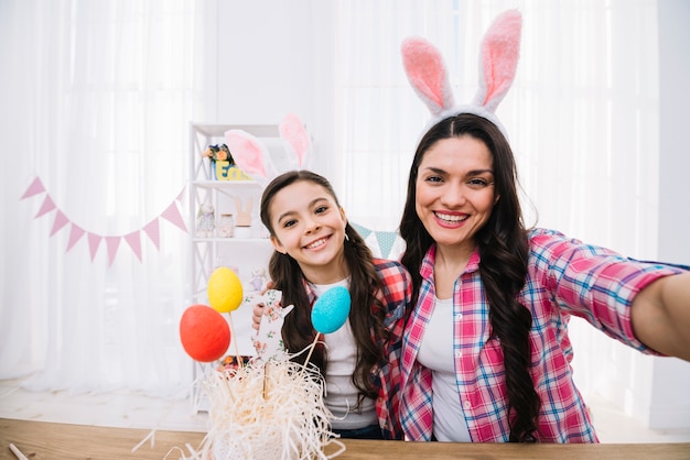 Uova di Pasqua variopinte davanti a madre e figlia che prendono selfie a casa