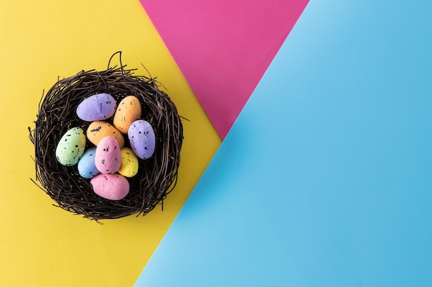 Foto gratuita uova di pasqua colorate all'interno di un nido su sfondo colorato