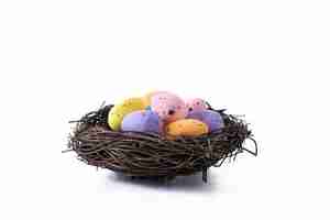 Free photo colorful easter eggs inside a nest isolated on white background