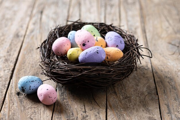 Красочные пасхальные яйца внутри гнезда на деревянном столе