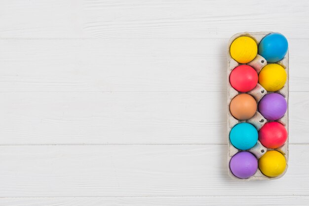 Colorful Easter eggs in rack on wooden table