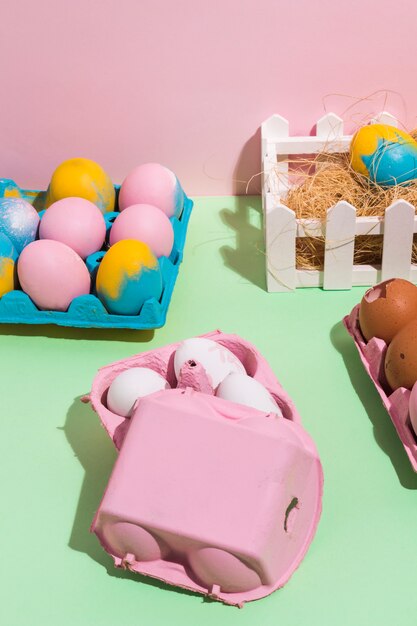 Colorful Easter eggs in racks and on hay on table