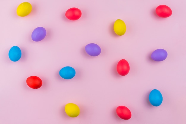 Free photo colorful easter eggs scattered on pink table