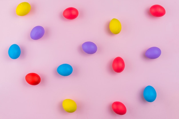 핑크 테이블에 흩어져있는 다채로운 부활절 달걀