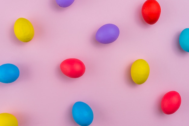 Colorful Easter eggs scattered on pink table