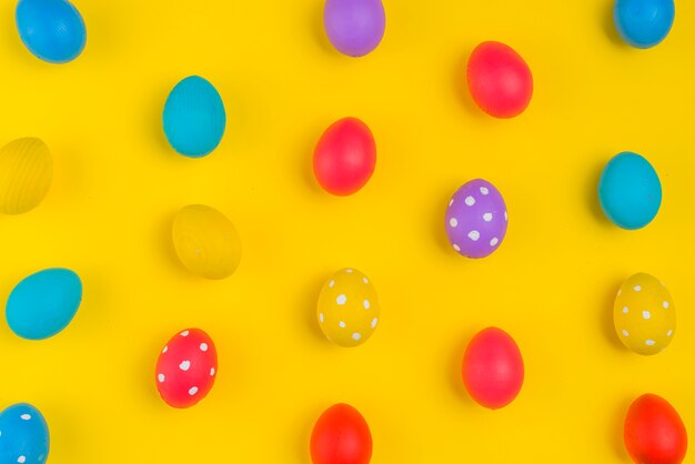 Colorful Easter eggs scattered on yellow table