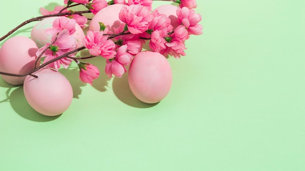 Foto gratuita uova di pasqua variopinte con i fiori sulla tavola verde