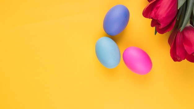 Colorful Easter eggs with tulips on table