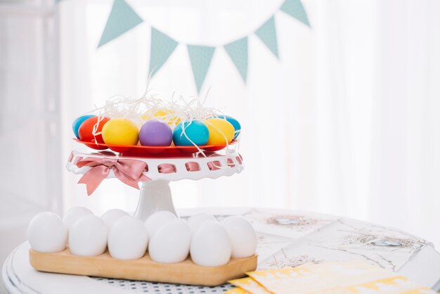 Colorful easter eggs with white eggs on table at home