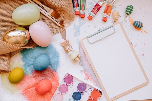 Colorful eggs and paper tablet on table