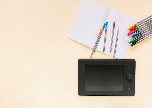 Бесплатное фото Красочные фломастеры на ноутбуке с графическим цифровым планшетом на цветном фоне