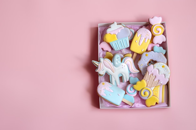 Colorful festive gingerbread cookies of different shapes covered with glaze on pink background copy space.