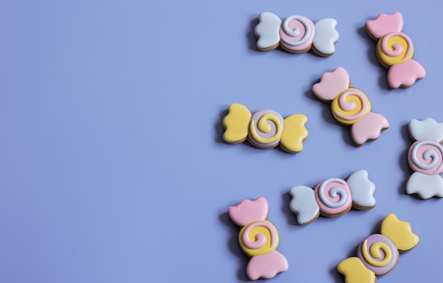 Colorful festive gingerbread cookies in the form of candies covered with glaze on a blue background copy space.