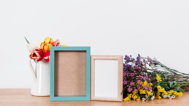 Colorful flowers and photo frames on table