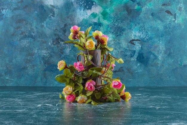 Colorful flowers in a wooden jug , on the blue background.