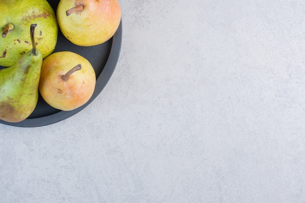 Colorful fresh pears on black plate. 