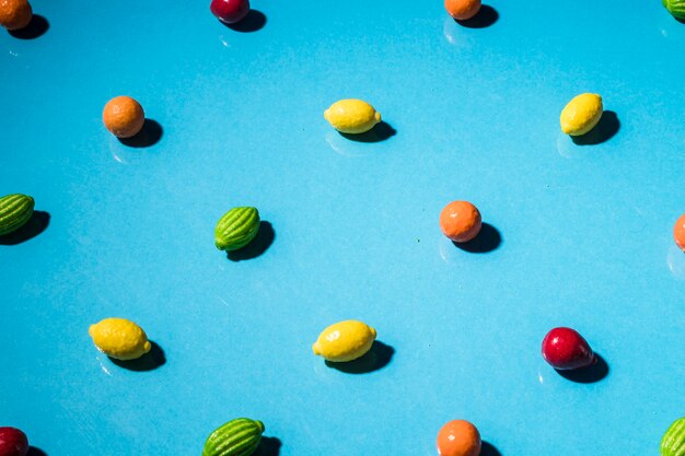 Colorful fruit shape candies on blue wallpaper