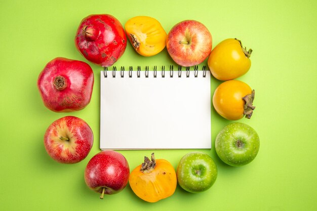 colorful fruits persimmons apples pomegranate next to the white notebook