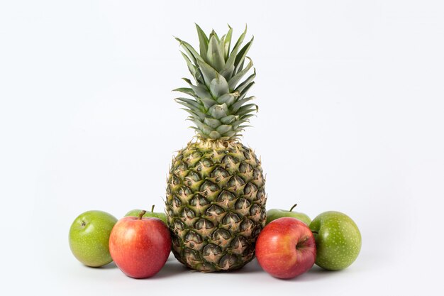 Colorful fruits ripe juicy pineapple and colored apples on a white desk