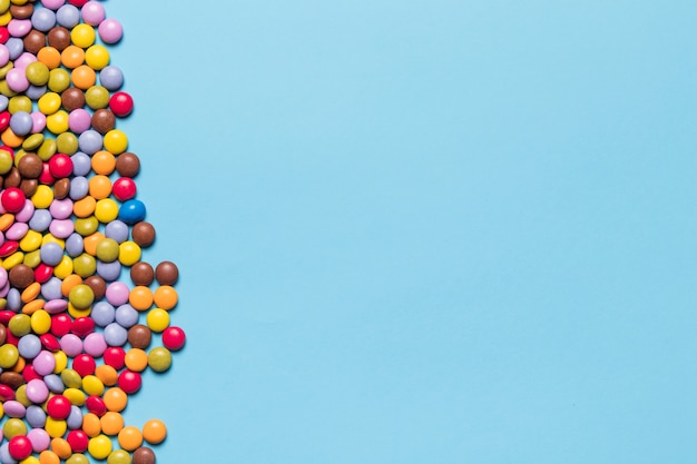 Colorful gem candies on the side of blue background