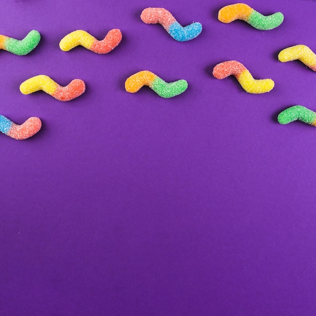 Бесплатное фото Красочные липкие червячные конфеты на фиолетовом фоне