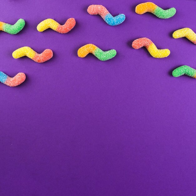 Colorful gummy worm candies on purple backdrop