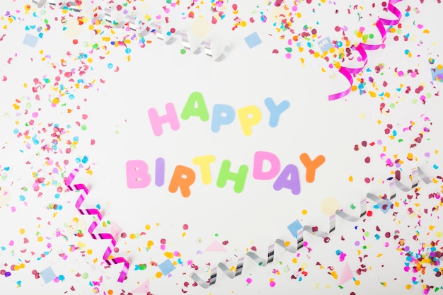 Free photo colorful happy birthday text with confetti and curling streamers on white background