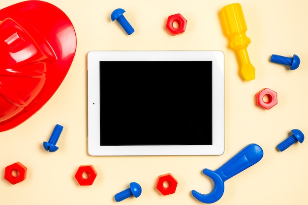 Colorful hardhat; screws; bolts; spanner tool and screwdriver around the digital tablet