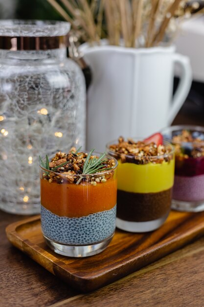 Colorful healthy breakfast sweet deserts few different chia puddings in glass jars on wooden table in kitchen at home.