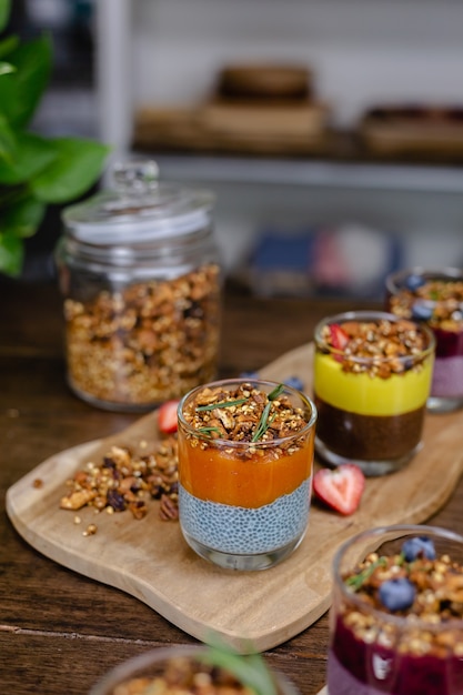 Красочный здоровый завтрак сладкие пустыни несколько разных пудингов чиа в стеклянных банках на деревянном столе на кухне дома.