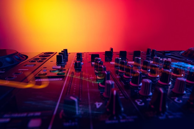 Colorful image of professional dj mixer isolated over gradient red yellow background in neon