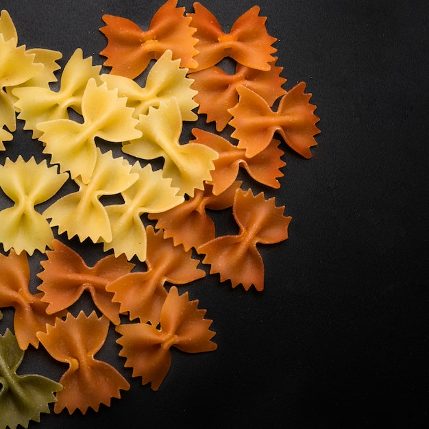 Free photo colorful italian bow tie fresh pasta on black background