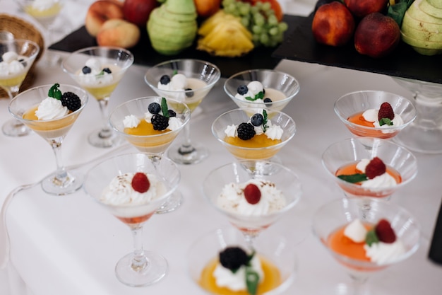 Colorful jelly desserts with berries and cream in the glassware on the banquet buffet